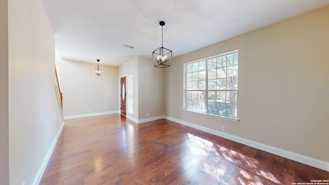 empty room featuring hardwood / wood-style flooring and a chandelier