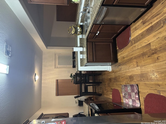 kitchen with dark brown cabinetry and wood walls