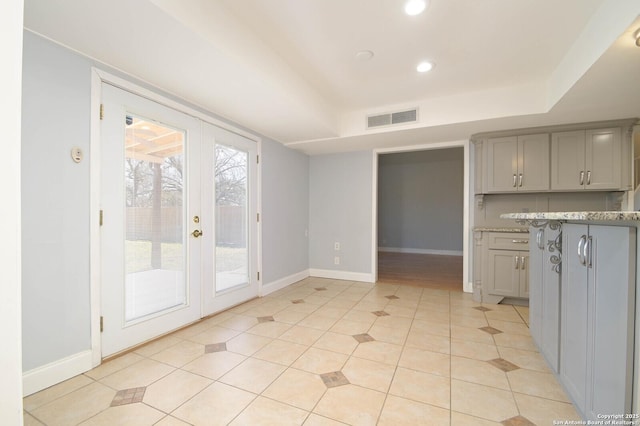 kitchen with gray cabinetry, light tile patterned floors, a raised ceiling, and french doors