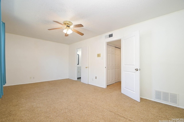 empty room with light colored carpet, a textured ceiling, and ceiling fan