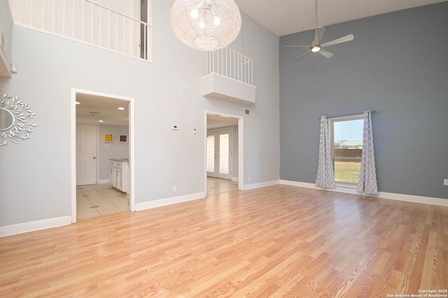 unfurnished living room with ceiling fan with notable chandelier and light wood-type flooring