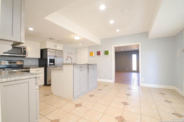 kitchen with stainless steel appliances, a center island with sink, white cabinets, and light stone counters