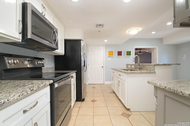 kitchen featuring light tile patterned flooring, appliances with stainless steel finishes, white cabinetry, sink, and light stone counters