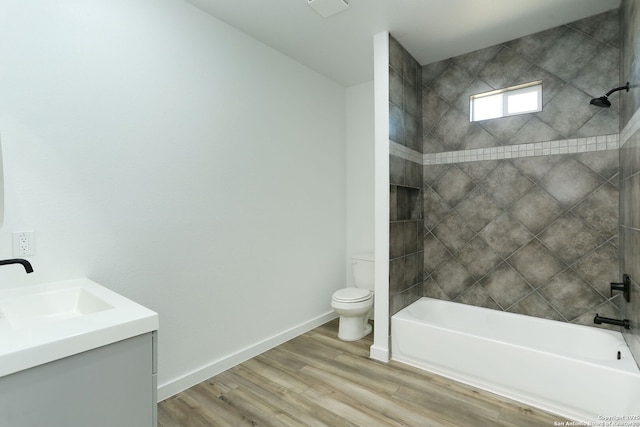 full bathroom featuring hardwood / wood-style flooring, vanity, tiled shower / bath, and toilet