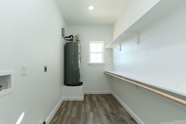 spacious closet featuring dark hardwood / wood-style flooring and water heater