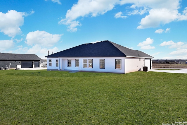 back of property with central AC, a garage, and a lawn