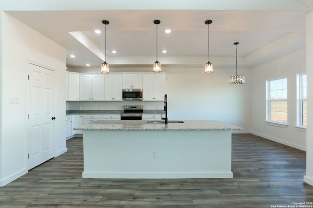 kitchen featuring stainless steel appliances, hanging light fixtures, a kitchen island with sink, and white cabinets