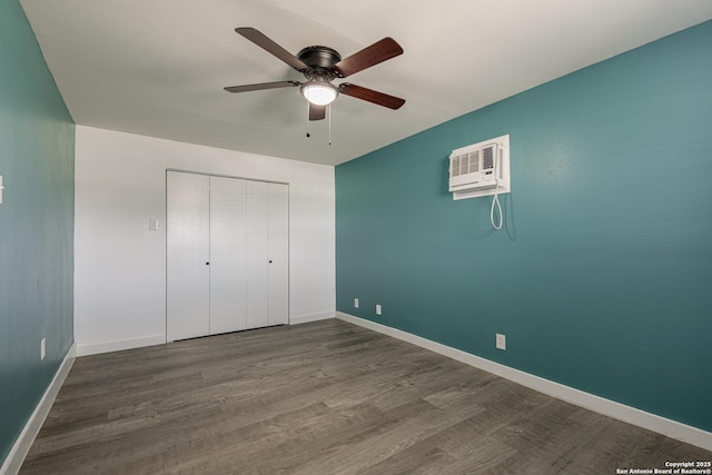 unfurnished bedroom with a closet, wood-type flooring, an AC wall unit, and ceiling fan