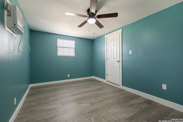 empty room featuring hardwood / wood-style flooring, an AC wall unit, and ceiling fan