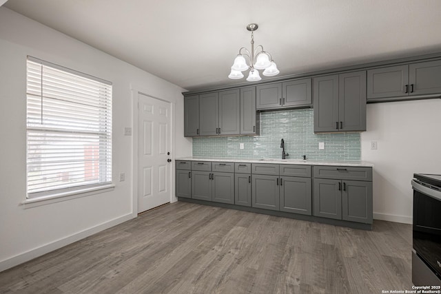 kitchen featuring sink, gray cabinets, backsplash, a notable chandelier, and stainless steel electric stove