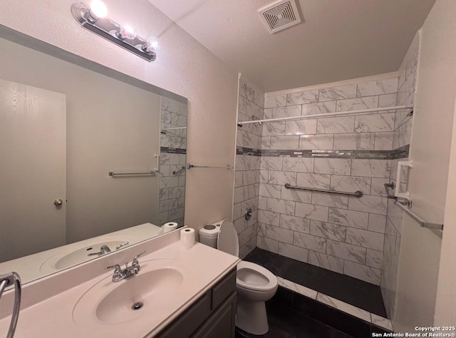 bathroom with vanity, toilet, and a tile shower