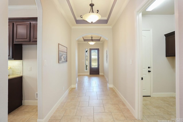 tiled entryway with crown molding and a raised ceiling