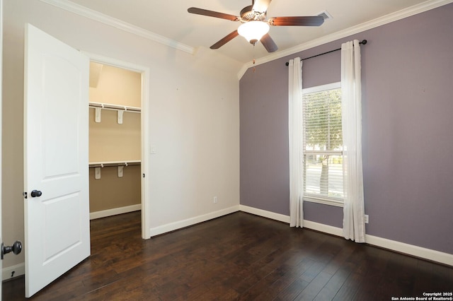 unfurnished bedroom with dark hardwood / wood-style flooring, a spacious closet, ceiling fan, crown molding, and a closet