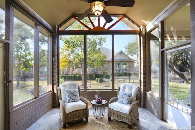 sunroom with ceiling fan, plenty of natural light, and vaulted ceiling