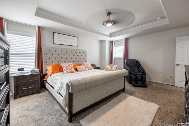 bedroom with ornamental molding, light colored carpet, ceiling fan, and a tray ceiling