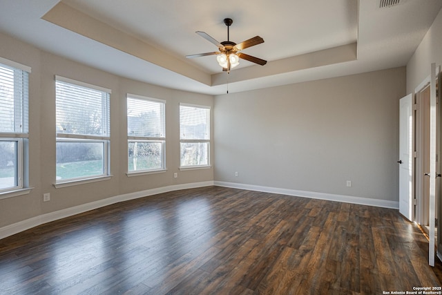 unfurnished room featuring a raised ceiling, dark hardwood / wood-style floors, and ceiling fan