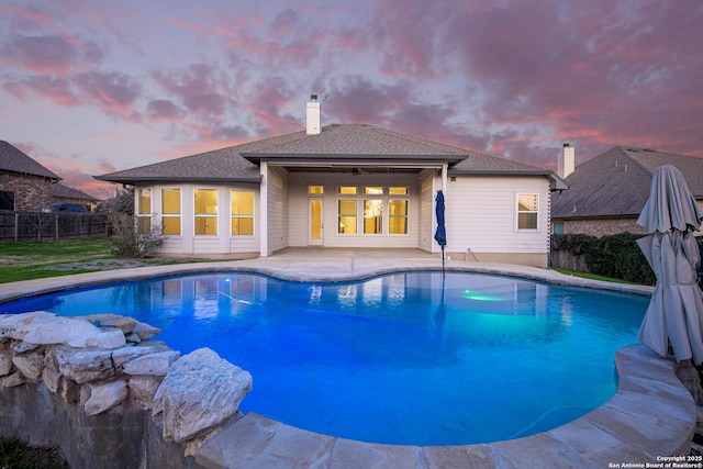 pool at dusk with a patio area