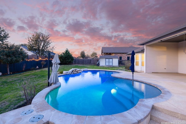 pool at dusk featuring a shed, a lawn, and a patio area