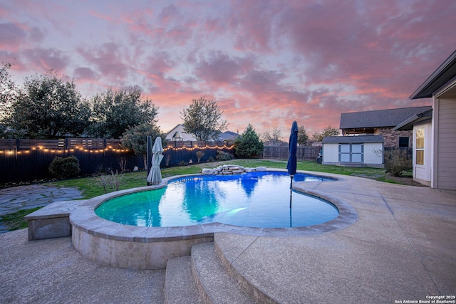 pool at dusk with a patio and a shed