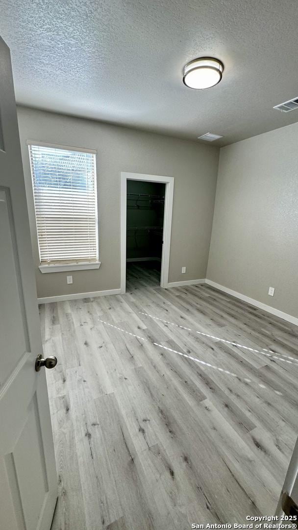 spare room featuring light hardwood / wood-style floors and a textured ceiling