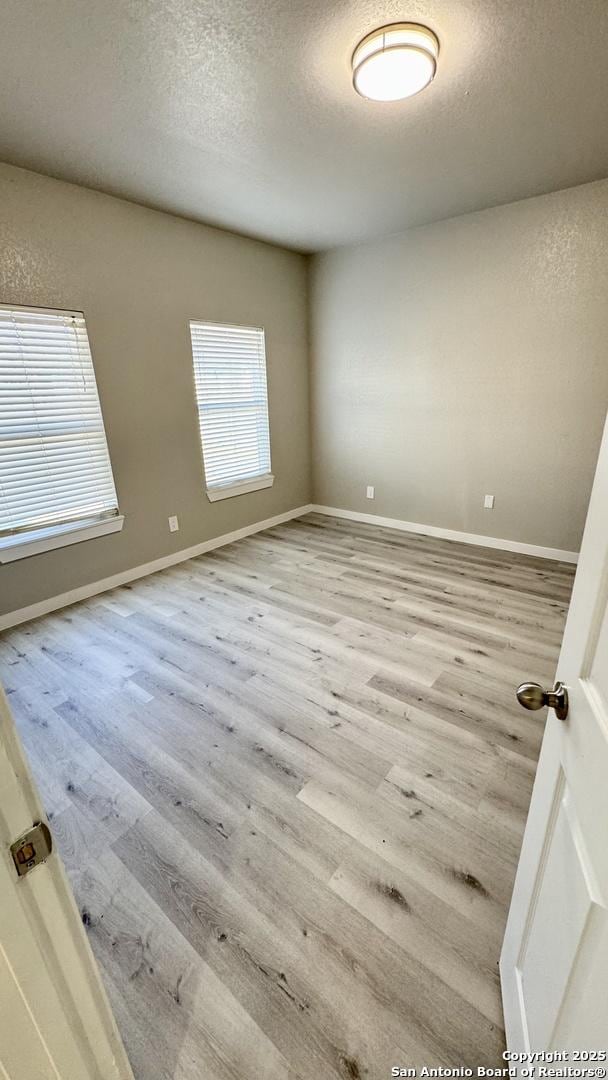 unfurnished room featuring a textured ceiling and light hardwood / wood-style floors