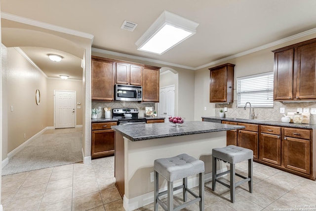 kitchen with crown molding, stainless steel appliances, a center island, and a breakfast bar