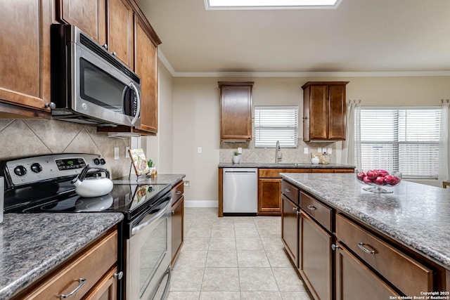 kitchen featuring light tile patterned flooring, sink, backsplash, ornamental molding, and stainless steel appliances