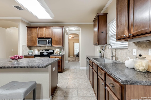 kitchen with a breakfast bar, sink, crown molding, light tile patterned floors, and appliances with stainless steel finishes