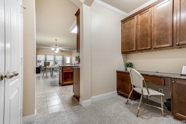 office featuring light colored carpet, built in desk, and ornamental molding