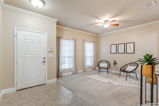 carpeted foyer featuring ceiling fan, crown molding, and a textured ceiling