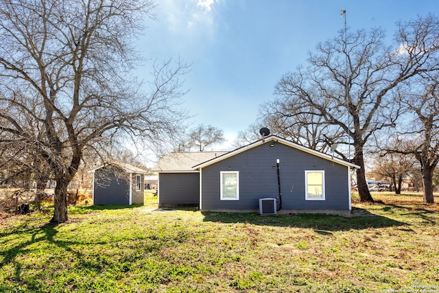 rear view of property featuring a storage shed, cooling unit, and a lawn