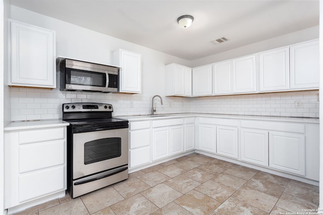 kitchen with tasteful backsplash, sink, white cabinets, and appliances with stainless steel finishes