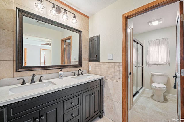 bathroom with tile walls, vanity, a shower with door, and toilet