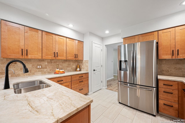 kitchen with light stone counters, sink, stainless steel fridge with ice dispenser, and tasteful backsplash