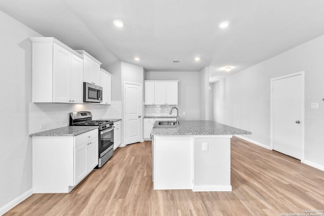 kitchen with sink, light hardwood / wood-style flooring, appliances with stainless steel finishes, an island with sink, and white cabinets