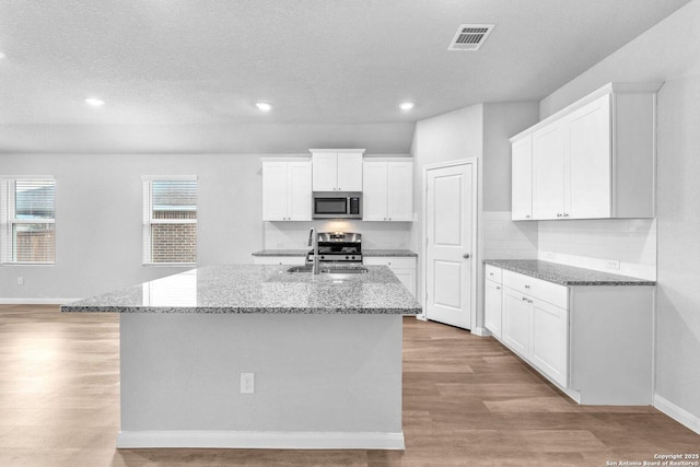 kitchen featuring an island with sink, appliances with stainless steel finishes, sink, and white cabinets