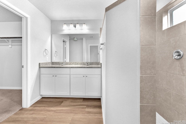 bathroom featuring wood-type flooring, vanity, and a textured ceiling