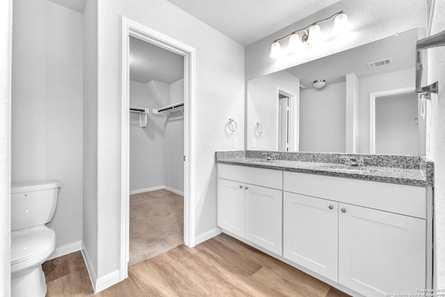 bathroom with wood-type flooring, vanity, a textured ceiling, and toilet