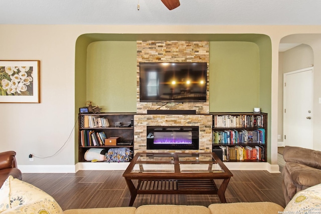 living room with a stone fireplace and ceiling fan