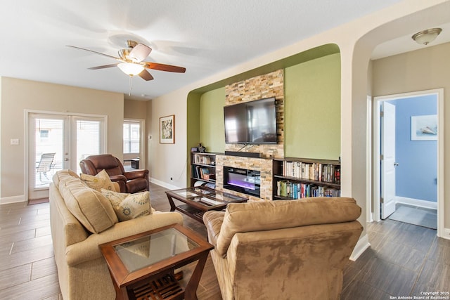 living room with ceiling fan, a stone fireplace, and hardwood / wood-style floors