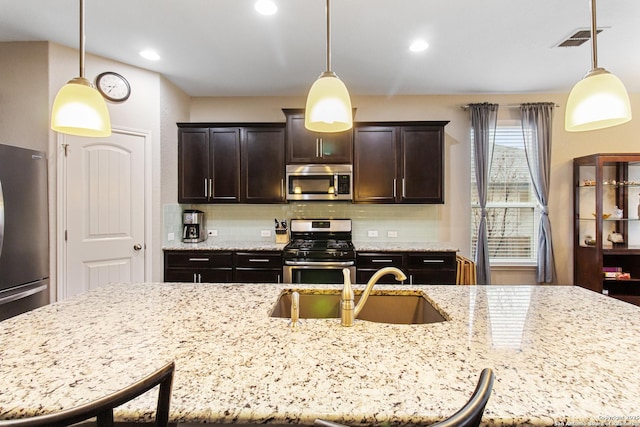 kitchen with stainless steel appliances, hanging light fixtures, sink, and dark brown cabinets