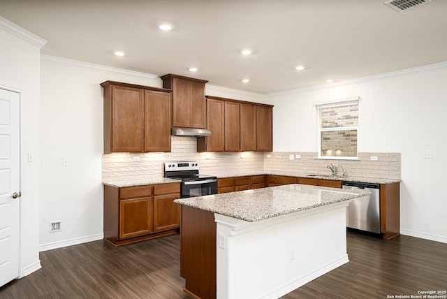 kitchen with appliances with stainless steel finishes, dark hardwood / wood-style floors, sink, a center island, and light stone counters