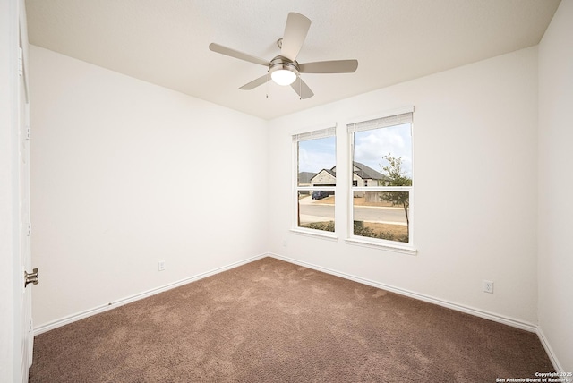 empty room with ceiling fan and dark carpet