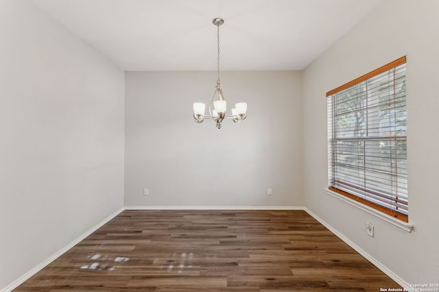 empty room featuring dark hardwood / wood-style floors and a chandelier