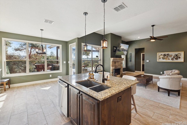 kitchen featuring pendant lighting, sink, stainless steel dishwasher, and light stone countertops