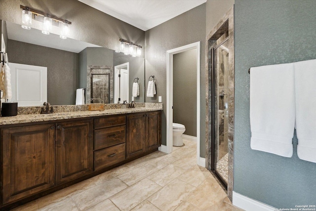 bathroom featuring vanity, a shower with shower door, and toilet