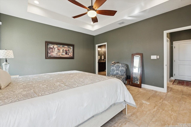 bedroom featuring ensuite bathroom, ceiling fan, and a tray ceiling