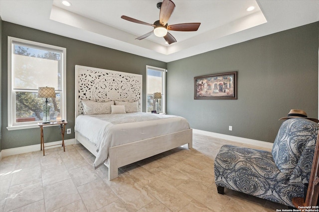 bedroom with ceiling fan and a raised ceiling