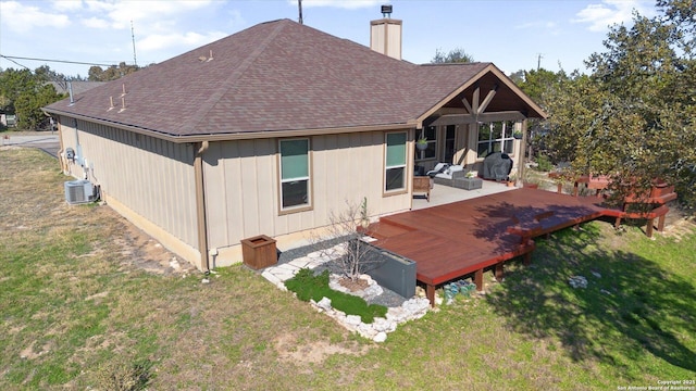 rear view of house featuring cooling unit, a wooden deck, a lawn, and a patio area