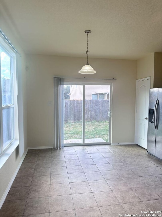 unfurnished dining area featuring light tile patterned floors and a textured ceiling